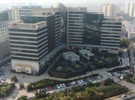 This is a JMD Megapolis building showcasing a high-angle drone view of the expansive, curved commercial complex facade, highlighting the outdoor visitor parking layout, retail storefronts, and landscaped entryways.