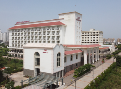 This is a JMD Suburbio 67 building showcasing a wide elevated view of its multi-story structure with prominent red tile roofing and individual step-out balconies, featuring the JMD Suburbio-67 and JMD Imperial Suites signage alongside a paved entryway.