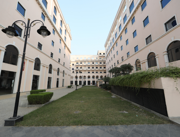 This is a JMD Empire building showcasing the wide, landscaped central green courtyard situated between two parallel corporate wings, featuring decorative street lamps and manicured hedges.