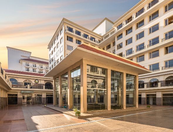This is a JMD Suburbio 67 building showcasing an open-air central courtyard view, highlighting a modern multi-tiered glass pavilion structure surrounded by multi-level retail shops and corporate office wings.