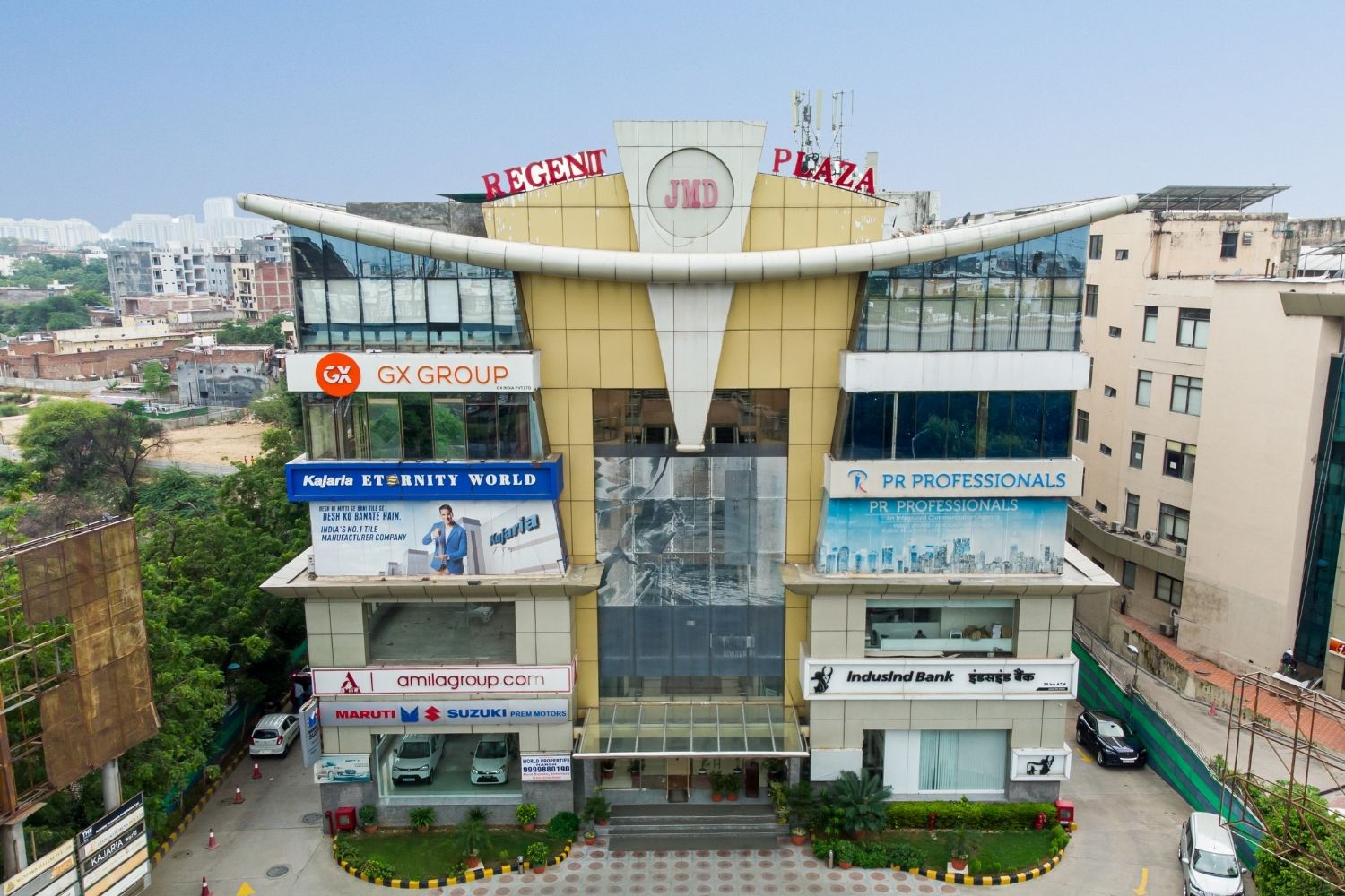 Aerial front view of JMD Regent Plaza on Mehrauli-Gurgaon Road, showcasing multiple corporate and retail signs.