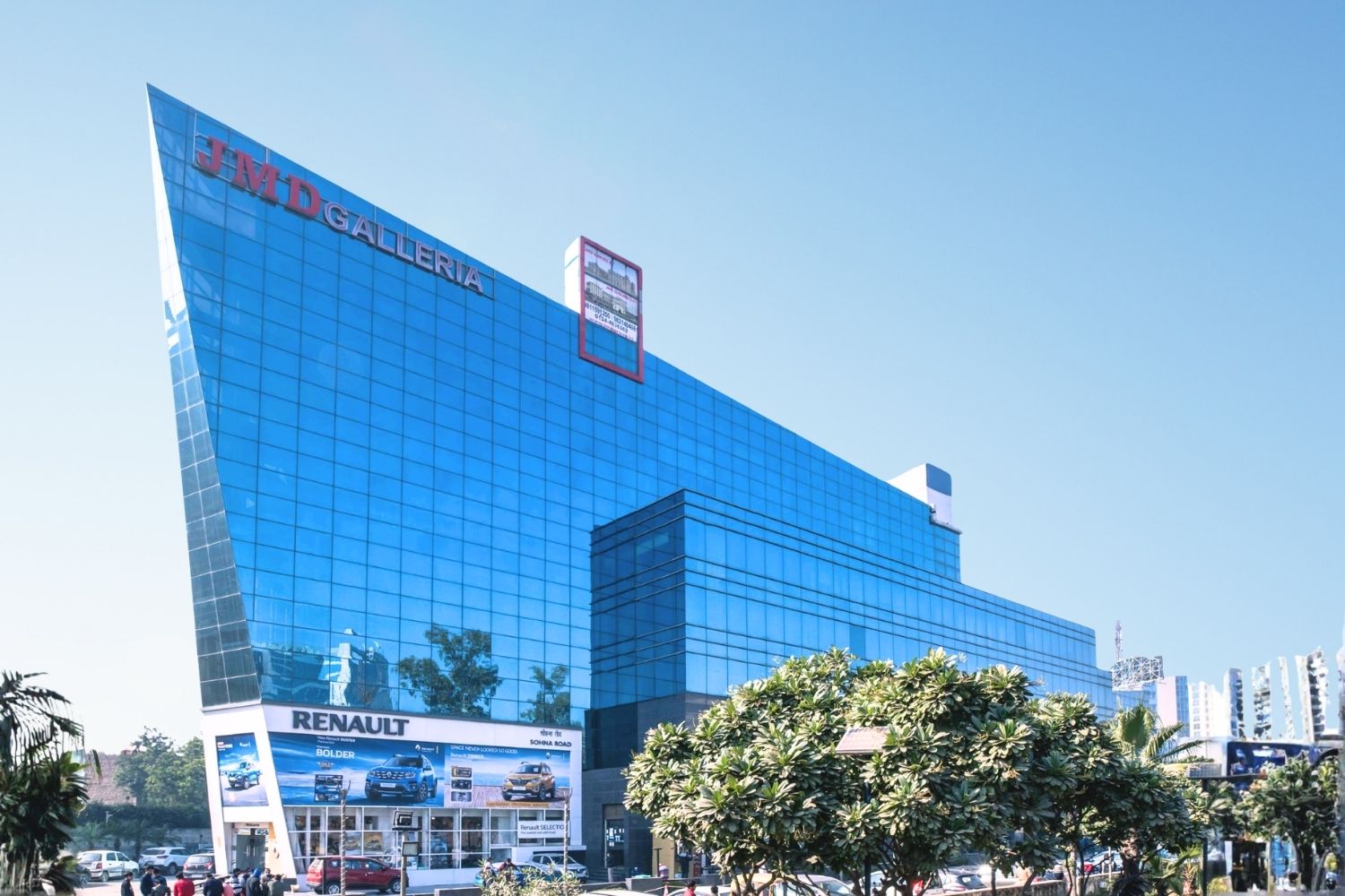 Distinctive angular blue glass architecture of JMD Galleria in Gurugram with a Renault showroom at the base.